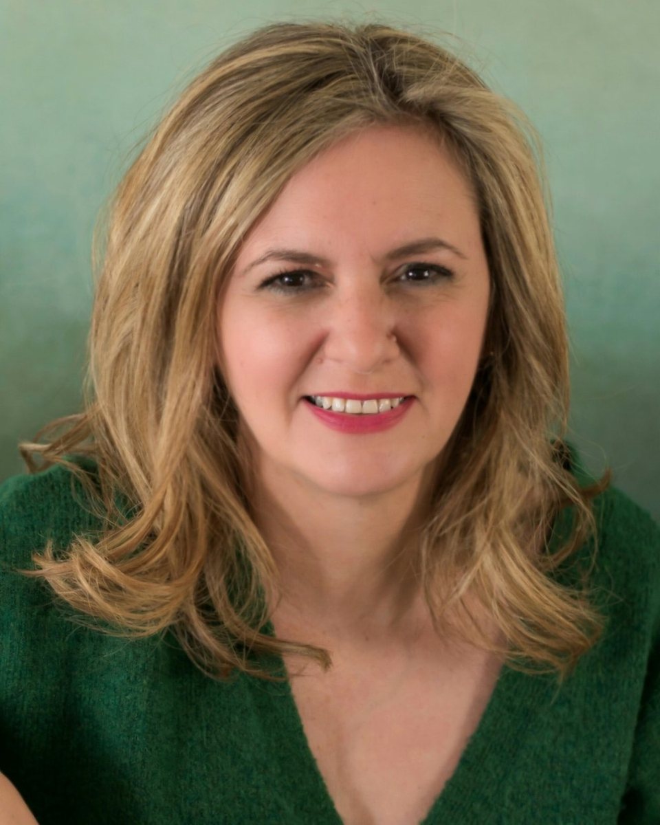Eleni Ispoglou, smiling, in a green cardigan.